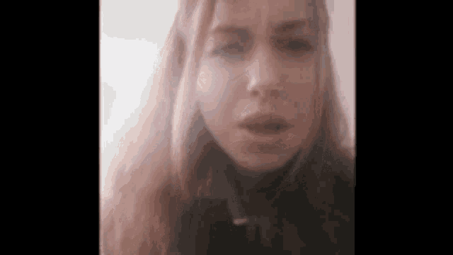 a close up of a woman 's face with long red hair looking at the camera .