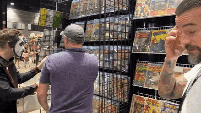 three men are looking at a display of comic books one of which is titled warriors of justice