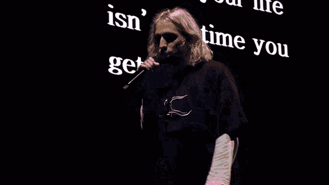 a man stands in front of a sign that says wasting your isn 't it time a