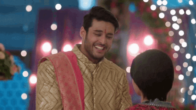 a man in a gold shirt is smiling at a woman