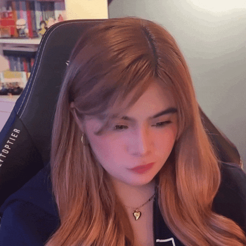 a woman wearing a heart shaped necklace is sitting in a chair that says eytoptier