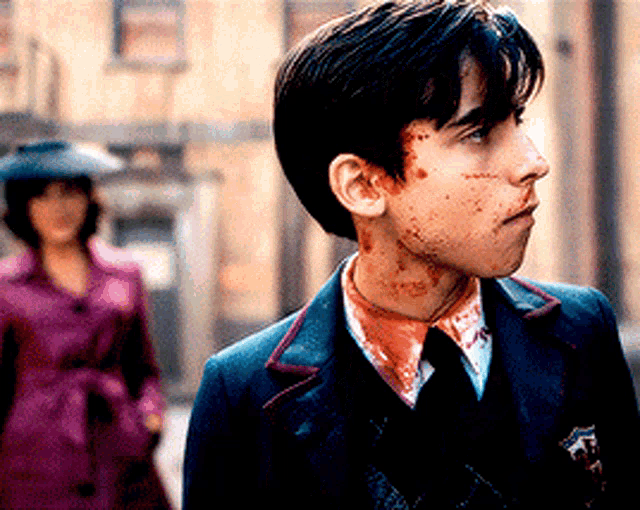 a man in a suit with blood on his face is walking down a street