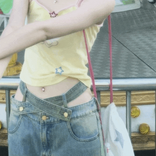 a woman wearing a yellow top and denim shorts
