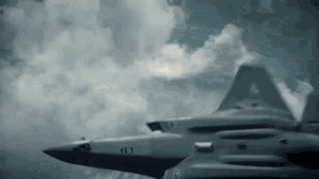 a fighter jet is flying in the sky with clouds .