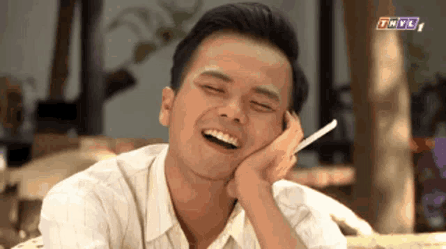 a man is laughing while talking on a cell phone with thvl written on the bottom right corner