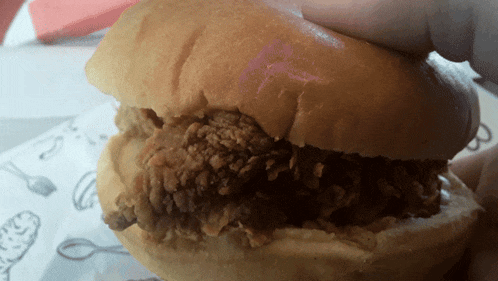 a person is holding a fried chicken sandwich