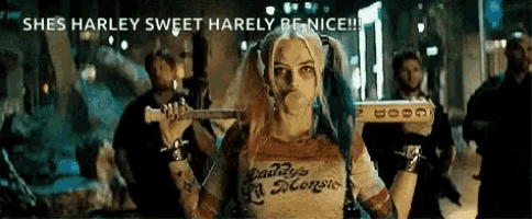 harley quinn from suicide squad is holding a bat and blowing bubble gum .