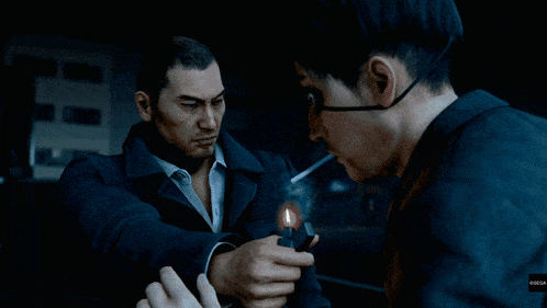 a man lighting another man 's cigarette with a lighter in a dark room