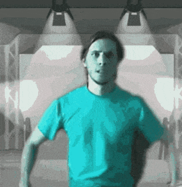 a man wearing a blue shirt is standing in front of a stage