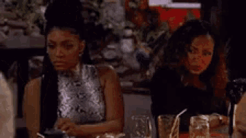 two women are sitting at a table in a restaurant with glasses of water .