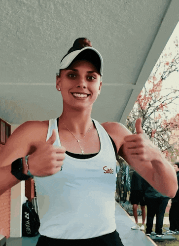 a smiling woman wearing a sadia tank top gives a thumbs up