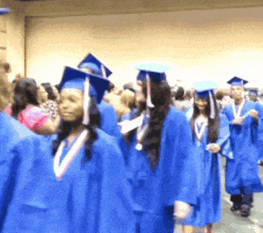 a group of graduates wearing blue gowns and caps walk in a line