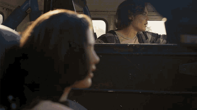 a man and a woman are looking out the window of a vehicle