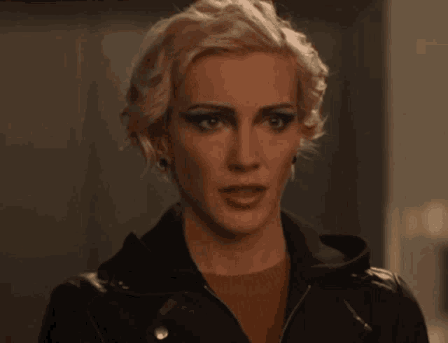 a woman with blonde hair is wearing a leather jacket