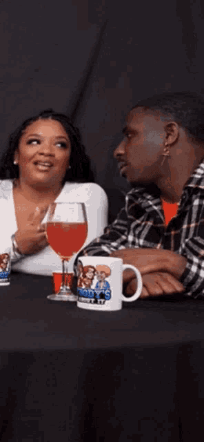 a man and woman are sitting at a table with a mug that says ' mom 's ' on it