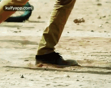 a close up of a person 's feet standing on a dirt ground .
