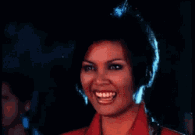 a woman in a red jacket is laughing with her mouth open .