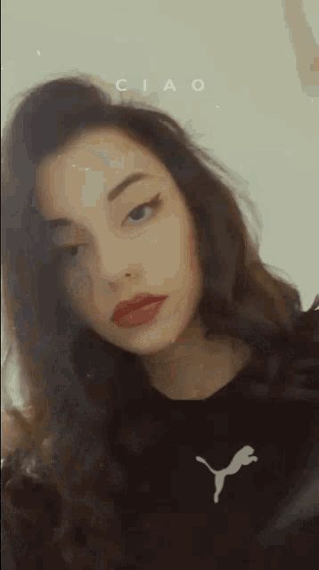 a woman wearing a black puma shirt is taking a selfie