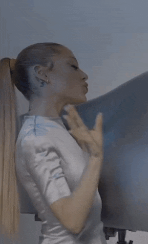 a woman in a white shirt with her hair in a ponytail .