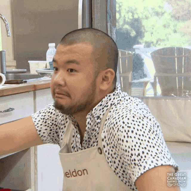 a man with a shaved head is wearing an apron that says eldon on it