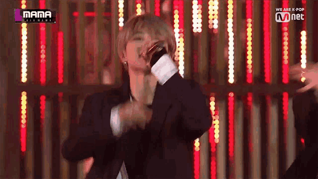 a man in a suit is singing into a microphone while dancing on a stage .