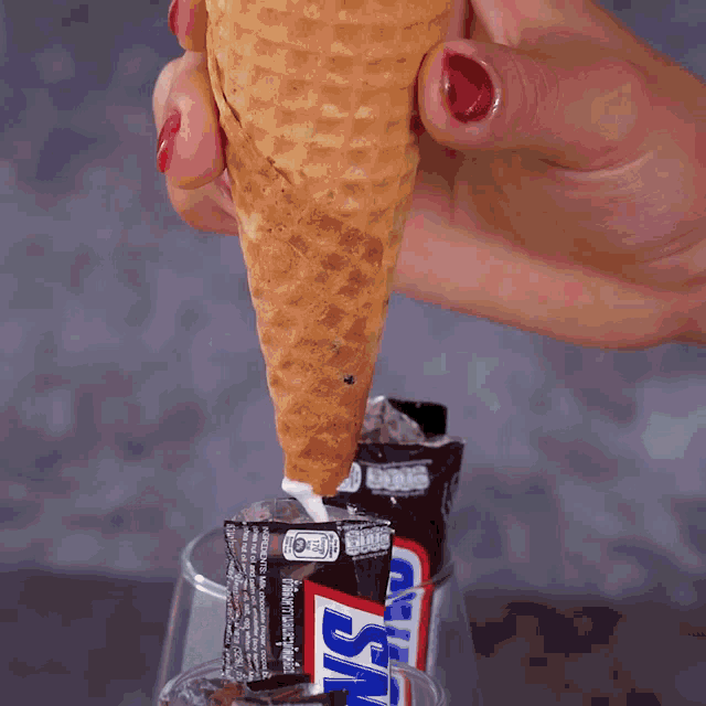 a person is dipping a stick into a glass of chocolate