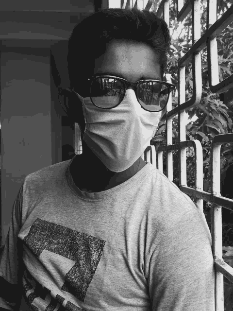 a young man wearing a face mask and sunglasses looks at the camera