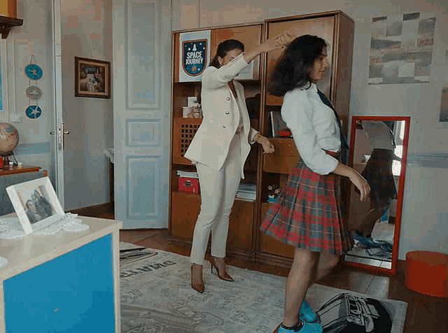 two women dancing in a room with a sign that says space shuttle