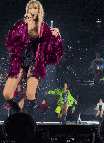 a woman in a pink fur coat singing into a microphone