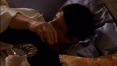 a man laying on a bed holding a silver plate