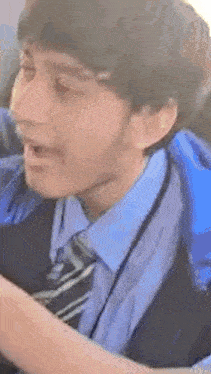 a man in a blue shirt and tie is sitting in a chair .