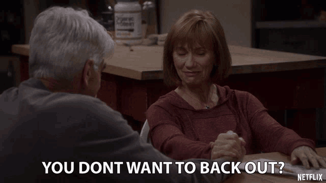 a man and a woman are sitting at a table and the woman is asking the man if he wants to back out