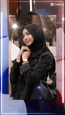 a woman wearing a black hijab and a black jacket is standing in front of a sign that says ' capcut '