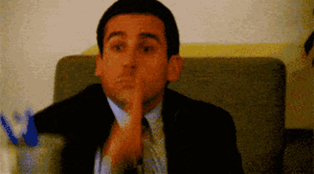 a man in a suit and tie is sitting in a chair with his hand on his chin