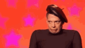a man wearing a beret and a black shirt is making a face .
