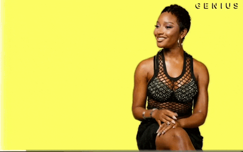 a woman is sitting in front of a yellow background that says genius on it