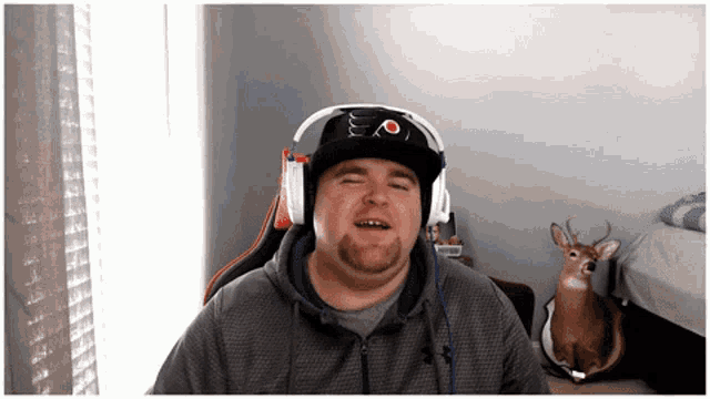 a man wearing headphones and a hat with the letter o on it smiles