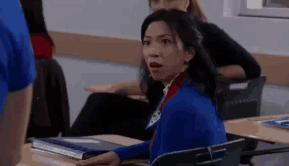 a woman is sitting at a desk in a classroom .