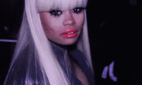 a woman with long blonde hair and red lips is looking at the camera .