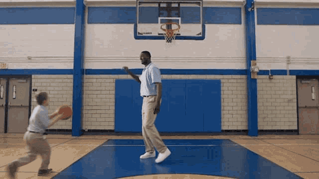a man and a boy are playing basketball on a court