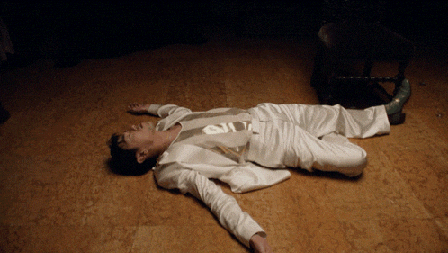 a man in a suit is laying on the floor with his arms outstretched