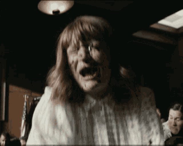 a woman in a white dress is screaming in front of a crowd
