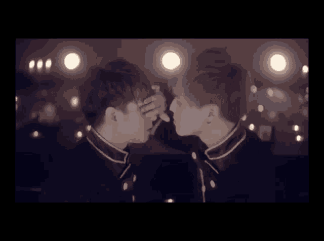 two young men are kissing in a dark room