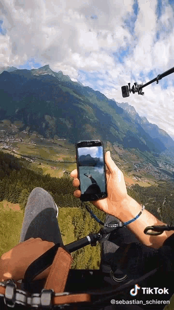 a person is holding a cell phone in front of a mountain with a tik tok watermark
