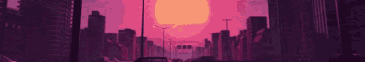 a sunset over a city with a lot of buildings and cars driving down a street .