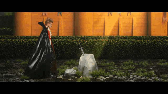a man in a black cape is standing next to a sword