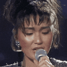 a woman is singing into a microphone with her eyes closed