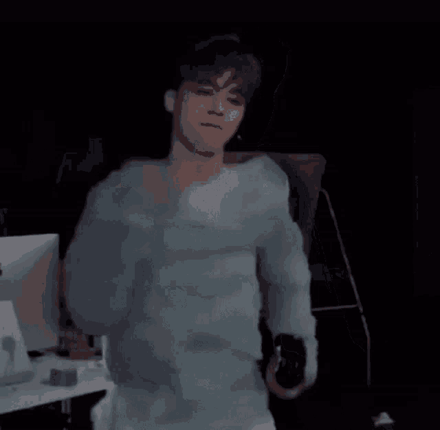 a man in a blue sweater is dancing in front of a computer .