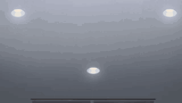 a ceiling with three lights on it and a gray background