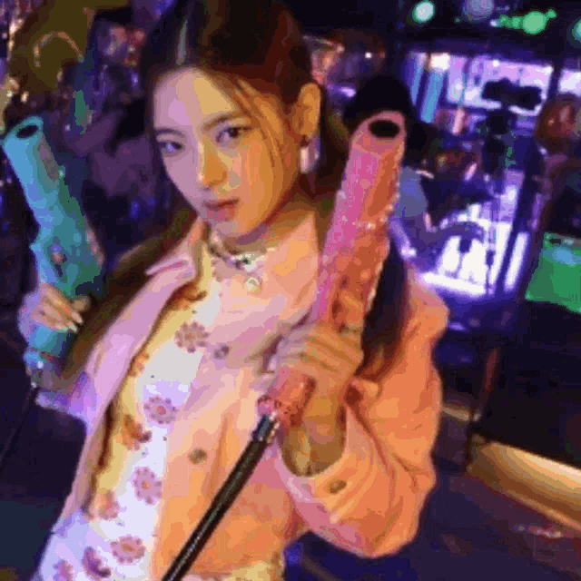 a girl in a pink jacket is holding a pink and blue umbrella
